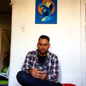 Oslec sits in his home in Santiago beneath a painting of J. Dilla. 